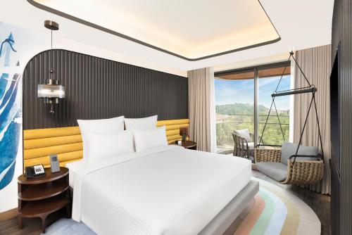 a bedroom with a white bed and a large window at Novotel Goa Panjim in Panaji