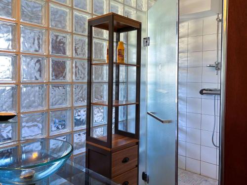 La salle de bains est pourvue d'un lavabo en verre et d'une douche. dans l'établissement Appartement 56m² bord de mer avec terrasse, parking privé, WiFi - FR-1-542-67, à Trébeurden