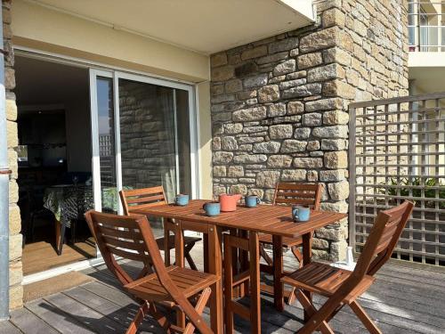 une table en bois avec des chaises et un mur en pierre dans l'établissement Appartement 56m² bord de mer avec terrasse, parking privé, WiFi - FR-1-542-67, à Trébeurden