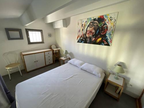 une chambre avec un lit blanc et un tableau au mur dans l'établissement Villa climatisée proche plage avec piscine et parking - FR-1-723-175, au Cap d'Agde