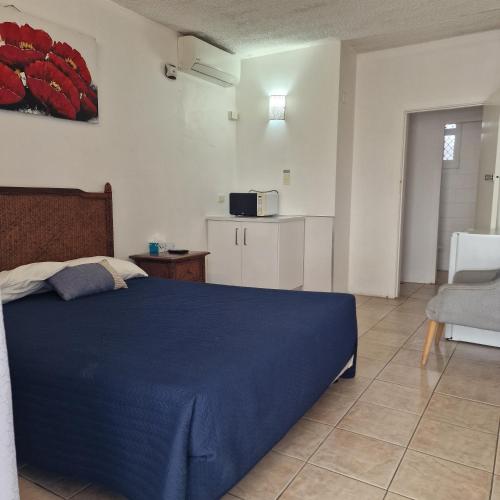 a bedroom with a blue bed and a kitchen at A1 Inn the city A1 Car Rentals in Cairns
