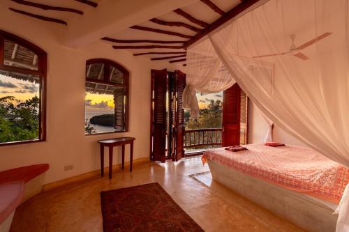 a bedroom with a bed in a room with windows at Fig House in Takaungu