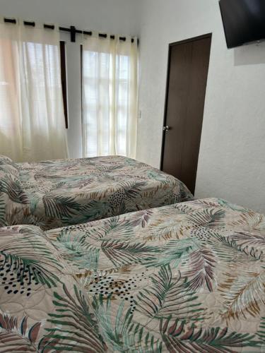 two beds in a bedroom with a bedspread with palm leaves at casa regina in Tepoztlán