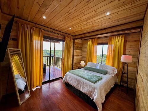 a bedroom with a bed and a balcony with yellow curtains at Cabaña Nora in Cedral
