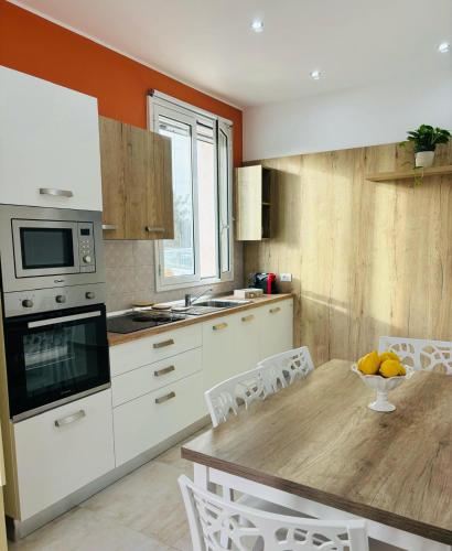 a kitchen with a wooden table and white cabinets at Come a casa in Solarino