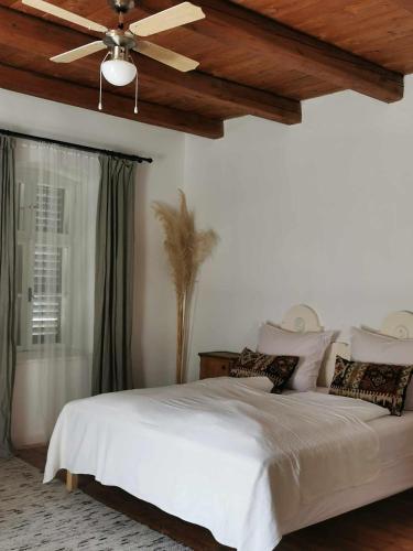 a bedroom with a white bed with a ceiling fan at Lelle Cottage in Balatonlelle