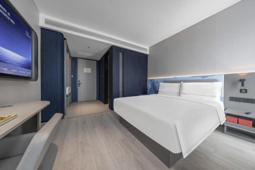 a bedroom with a large white bed and a desk at Atour Light Hotel Zhuhai Xiangzhou Mingzhu Station in Zhuhai