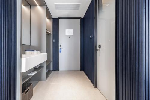 a bathroom with a white sink and a blue wall at Atour Light Hotel Zhuhai Xiangzhou Mingzhu Station in Zhuhai