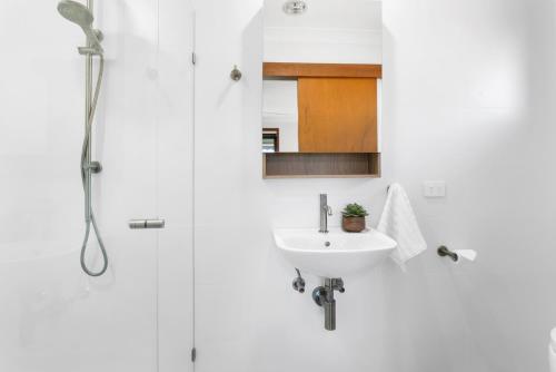a white bathroom with a sink and a shower at Shoal Bay Studio in Shoal Bay