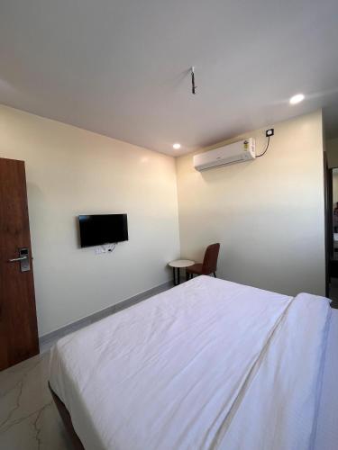 a bedroom with a bed and a tv on the wall at Hotel soumya sarovar in Jagdalpur