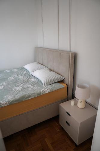 a bedroom with a bed and a nightstand with a lamp at Apartman Iskra in Bijeljina