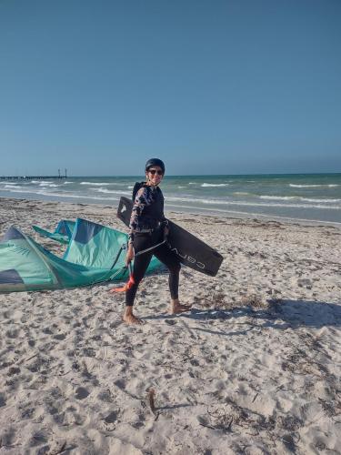 a man standing on the beach with a surfboard and a tent at Casita viento in El Cuyo