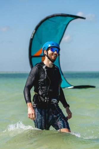 a man standing in the water with a wind sail at Casita viento in El Cuyo