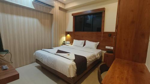 a hotel room with a bed and a television at Hotel Ashraya International in Mumbai