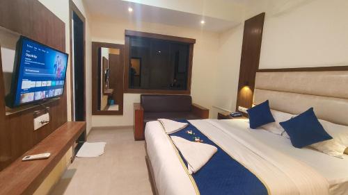 a hotel room with a large bed and a flat screen tv at Hotel Ashraya International in Mumbai