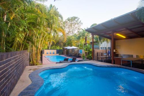 a swimming pool in a yard with a patio and trees at Quarterdecks Retreat in Hervey Bay