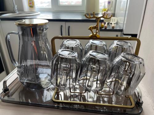a tray with a pitcher and six empty wine glasses at Уютная 2-х комнатная квартира in Taraz