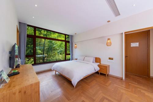 a bedroom with a bed and a large window at Anji Bamboo Homestay in Tangkou