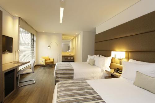 a hotel room with two beds and a desk at bs Rosales Hotel in Bogotá