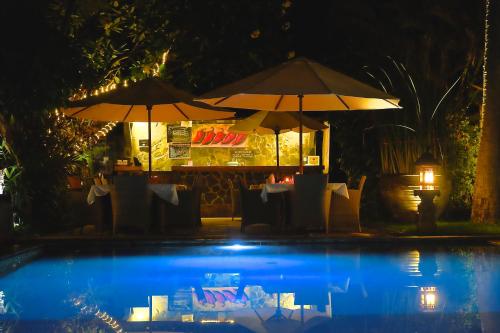 a restaurant with two umbrellas next to a pool at night at Villa Boreh Beach Resort and Spa in Tejakula