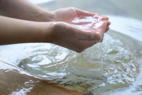 a person washing their hands in a bowl of water at Suigunnoyado in Ajigasawa