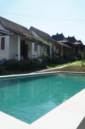 a swimming pool in front of a house at Berawagaya Bungalows in Dalung