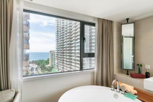 a bathroom with a large window and a tub and a sink at SSAW Boutique Hotel Sanya in Sanya
