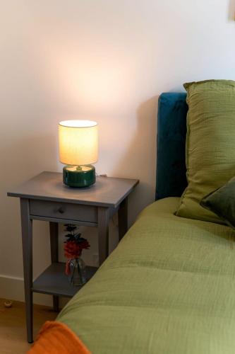 une lampe sur une table à côté d'un lit dans l'établissement Paris Élégance Private Parking et Metro 2 minutes, à Saint-Ouen