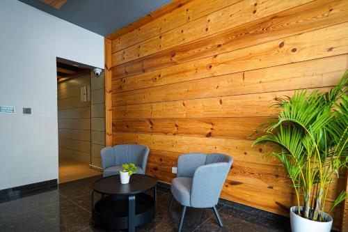 two chairs and a table in front of a wooden wall at Open Hotel by Olive - Moka in Bengaluru