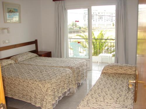 a bedroom with two beds and a balcony at Hostal Talamanca in Talamanca