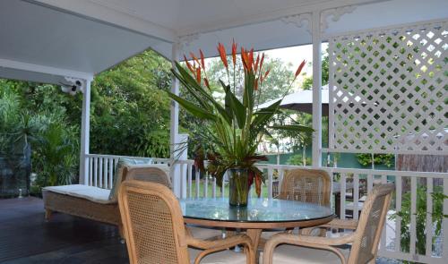 einen Tisch mit Stühlen und eine Topfpflanze auf einer Veranda in der Unterkunft South Pacific Bed & Breakfast in Clifton Beach