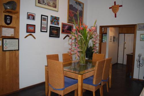 a dining room table and chairs with a vase of flowers at South Pacific Bed & Breakfast in Clifton Beach