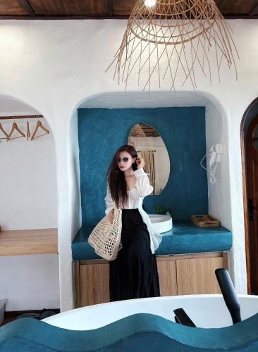 a woman sitting on a blue bench in front of a mirror at Santa Fe House - Gành Đá Đĩa in Phú Hạnh (5)