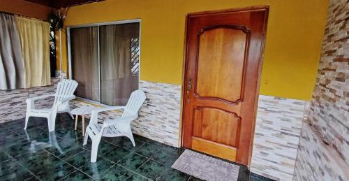 two white chairs and a table and a wooden door at El Corazón de Quepos in Quepos