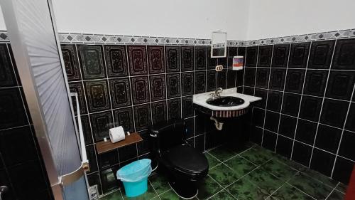 a black tiled bathroom with a toilet and a sink at El Corazón de Quepos in Quepos