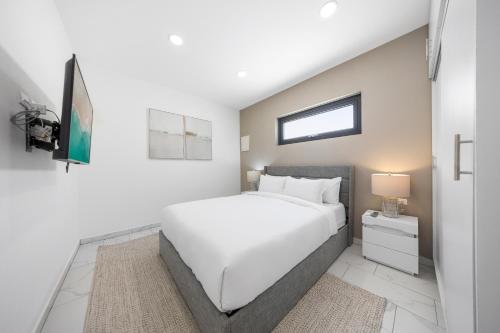 a white bedroom with a white bed and a window at Charming 2 BR Oasis in Oranjestad by Bocobay in Pos Abao