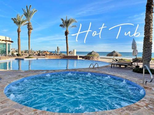 a swimming pool with palm trees and the words hot tub at Serenity by the Sea Stunning Beachfront Condo #1003 in Playa Encanto