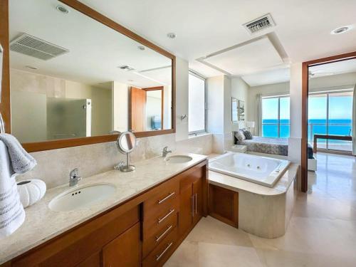 a bathroom with two sinks and a large mirror at Serenity by the Sea Stunning Beachfront Condo #1003 in Playa Encanto