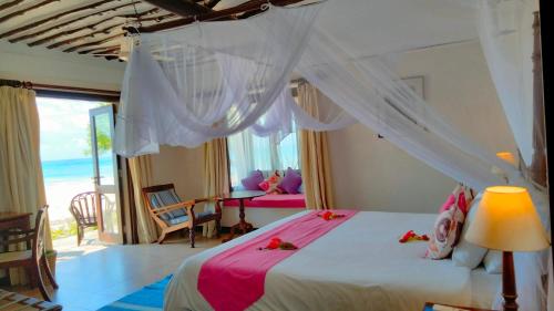 a bedroom with a canopy bed with a view of the ocean at Jacaranda Indian Ocean Beach Resort in Diani Beach
