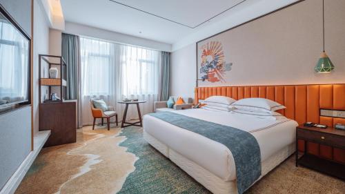 a hotel room with a large bed and a table at Wellay Hotel Ningbo Jiangbei Olympic Sports Center in Ningbo