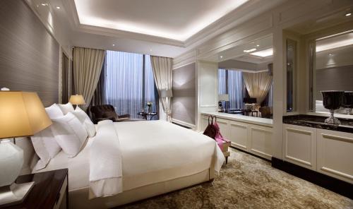 a bedroom with a large white bed and a large window at The Trans Luxury Hotel Bandung in Bandung