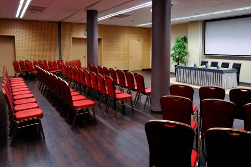 a conference room with red chairs and a screen at Ruben Hotel Zielona Góra in Zielona Góra
