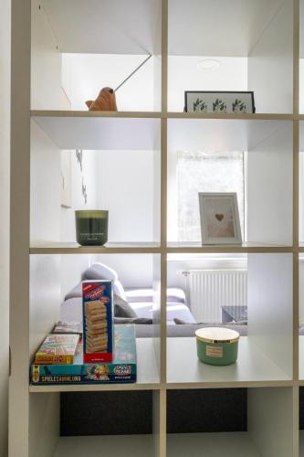 a white book shelf with food and a bed at Natur View Apartment in Kaltenleutgeben