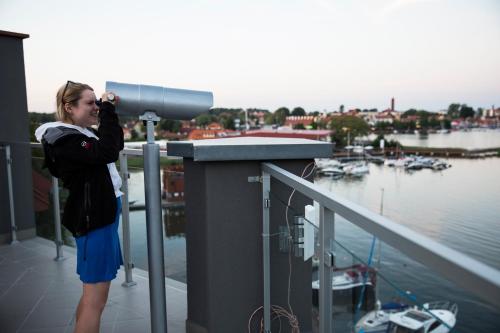 a woman standing on a balcony taking a picture of a marina at Ach Mazury in Mikołajki