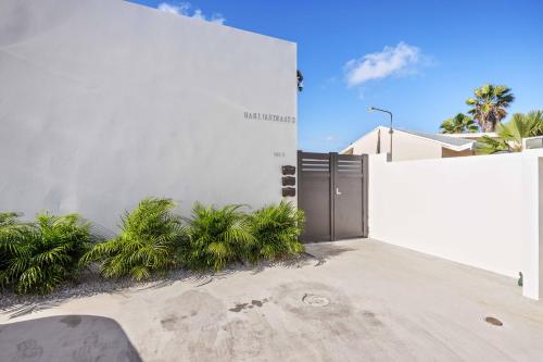 a white building with a gate and some plants at Charming 2 BR Oasis in Oranjestad by Bocobay in Pos Abao