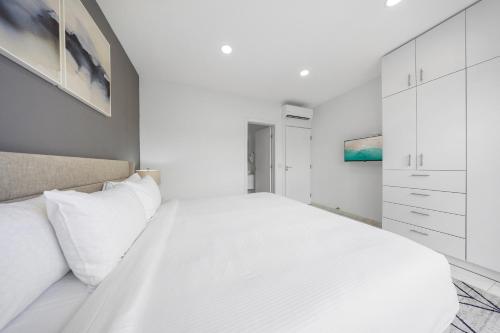 a white bedroom with a large bed with white cabinets at Charming 2 BR Oasis in Oranjestad by Bocobay in Pos Abao