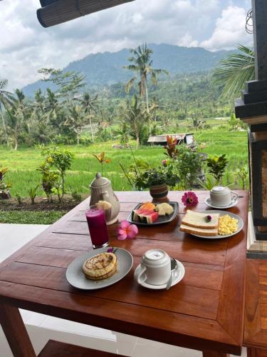 a wooden table with plates of food on it at Sarwhe Nadi Homestay in Sidemen