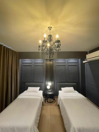 two beds in a room with a chandelier at Tara Valley Saraburi in Ban Chon