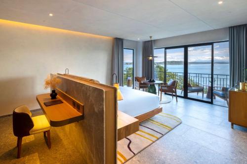 a bedroom with a bed and a desk and a balcony at Waldorf Astoria Costa Rica Punta Cacique in Playa Hermosa