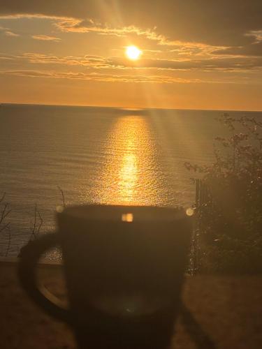a coffee cup sitting on a balcony with the sunset at Sunsea House Copanello in Copanello
